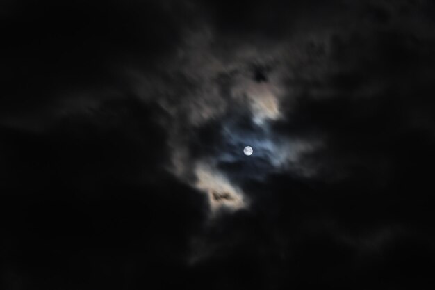 Ein Vollmond ist durch die Wolken sichtbar.