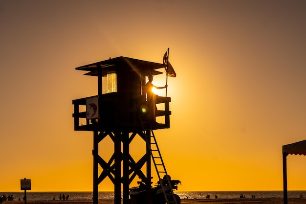 Ein Wächter, der im Sommer am Wächterposten bei Sonnenuntergang am Strand von Bateles in Conil de la Frontera Cadiz arbeitet