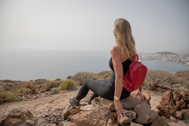 Ein Wanderer blickt auf das Meer, während er entspannt auf einem Felsen sitzt, Liebe zur Natur und zum Freiheitskonzept