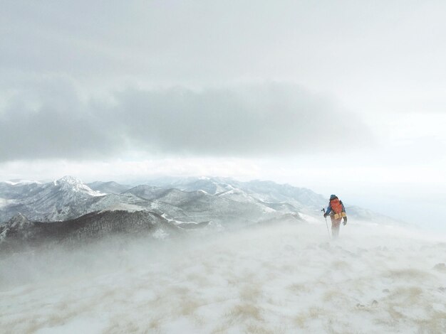 Foto ein wanderer steht auf einem schneebedeckten berg gegen den himmel