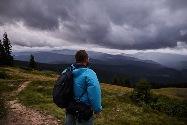 Ein Wanderer steht auf einer Bergwiese. Genießen Sie die Aussicht vor dem Sturm. Wandern in den Karpaten