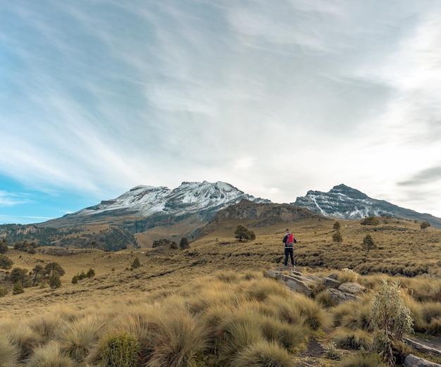 Ein Wanderer steht mit Rucksack vor dem Vulkan Iztaccihuatl