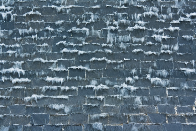 Ein Wasserfall an der schwarzen Steinmauer