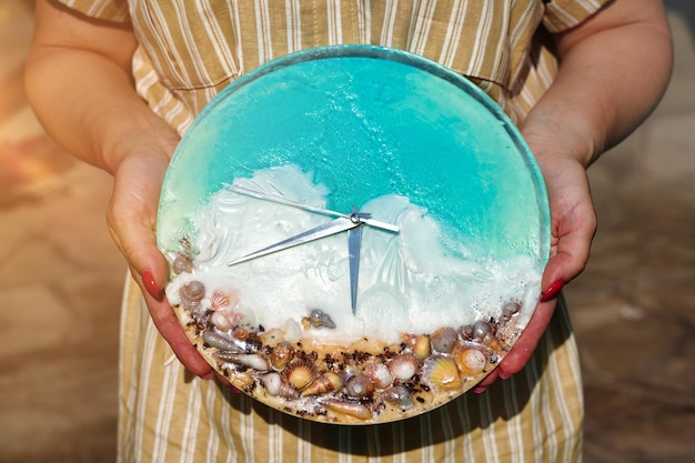 Ein Wecker mit Muscheln Meereswelle und Frau Hand Urlaubszeit senden Strandzeit