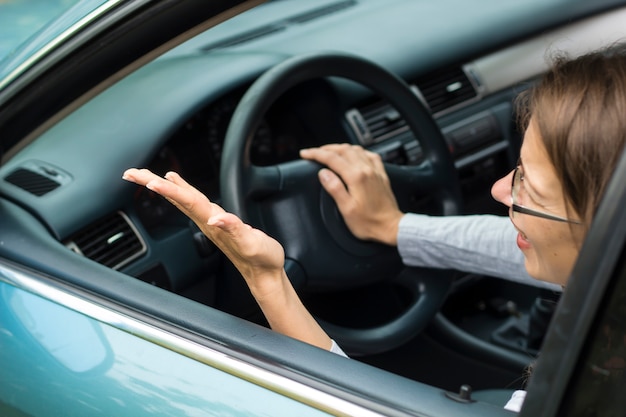 Ein weiblicher Fahrer sitzt nervös im Auto. Die Frau ist empört, schreit.