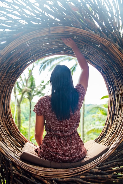 Ein weiblicher Tourist sitzt auf einem großen Vogelnest auf einem Baum in Bali-Insel