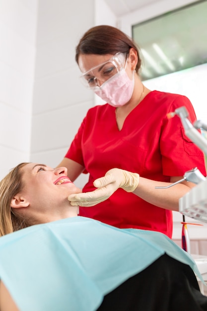 Ein weiblicher Zahnarzt, der ihren Patienten auf Karies überprüft