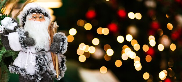 Ein Weihnachtsmann-Spielzeug in einem weißen Anzug steht auf einem dunklen Hintergrund mit Bokeh