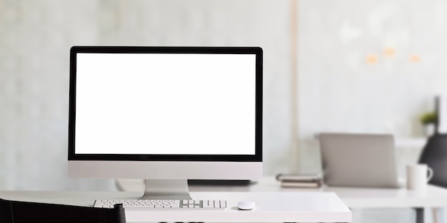 Ein weißer Computermonitor mit leerem Bildschirm stellt einen weißen Schreibtisch im Büro auf