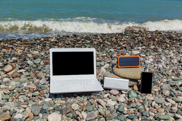 Ein weißer Laptop liegt auf Felsen nahe der Küste. Laptop auf dem Kies.