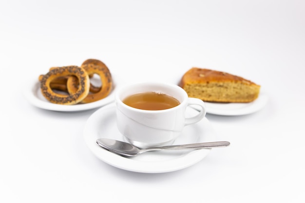 Ein weißer Tee-Set mit Teekanne Tee und Untertassen und Kuchen zum Frühstück