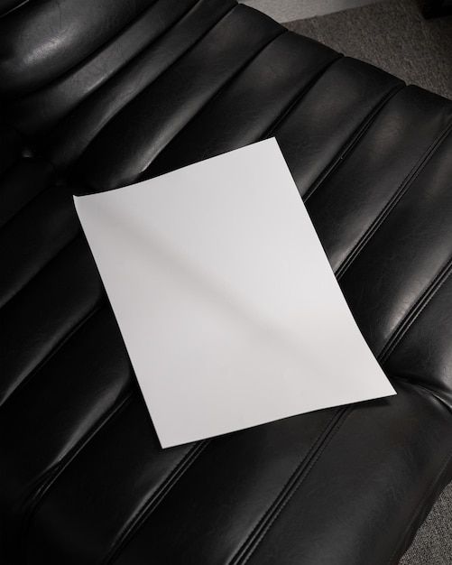 ein weißes A3-Papier auf einer schwarzen Ledercouch