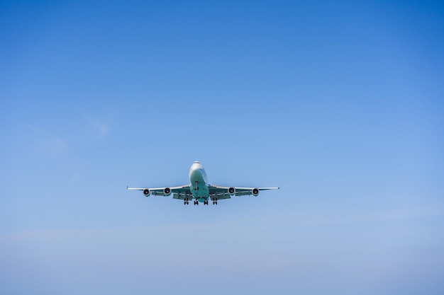 Ein weißes Flugzeug, das in einem klaren hellblauen Himmel fliegt