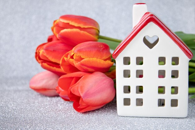 Foto ein weißes haus mit rotem dach und tulpen auf silbernem hintergrunddas thema liebe und feiern