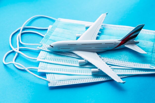 Ein weißes kommerzielles Flugzeug über einer Maske für Covid-19 und ein rotes Passbuch