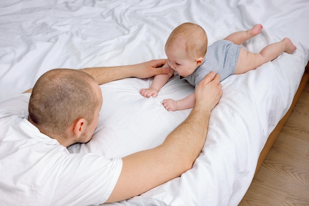 ein weiteres unterstützendes Baby, das auf dem Bett liegt, lehrt, sich auf den Bauch zu legen und sich auf den Bauch zu drehen