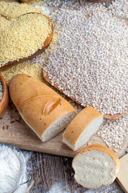 Ein Weizenbaguette auf dem Tisch mit Mehl und verschiedenen Pflanzenkörnern ein Küchentisch mit Brot und Zutaten dafür Brei und Reis