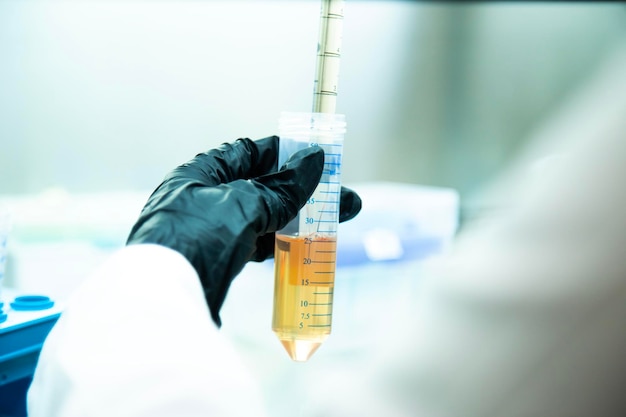 Foto ein wissenschaftler in einem labor, der einen handschuh trägt, hält ein reagenzglas mit flüssigkeit darin.