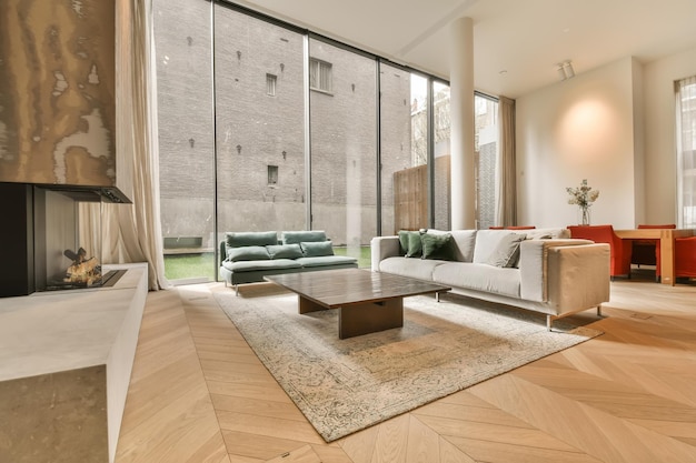 Ein Wohnzimmer mit Holzboden und großen Fenstern mit Blick auf den Gartenbereich vor dem Haus