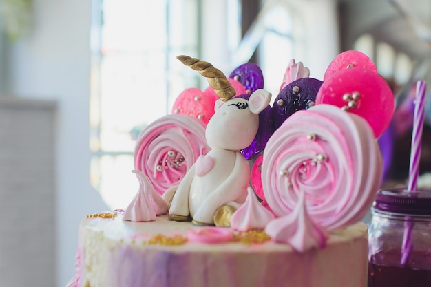 Foto ein wunderschöner, heller kuchen, der in form eines fantasie-einhorns in dem blauen bücherregal geschmückt ist, das konzept des