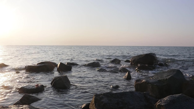 Ein wunderschöner Sonnenaufgang über dem Meer mit Steinhintergründen im Vordergrund