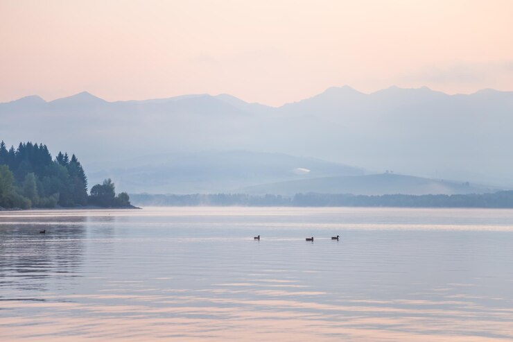 Foto ein wunderschöner sonnenaufgang über dem see mit bergen in der ferne morgenlandschaft in warmen tönen