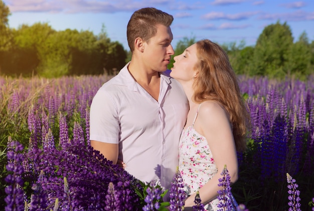 Ein wunderschönes junges verliebtes Paar, das sich in einem Blumenfeld küsst