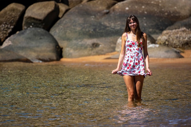 Ein wunderschönes langhaariges Mädchen in einem Kleid entspannt sich an einem paradiesischen Strand auf Magnetic Island, Australien