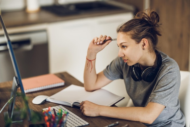 Foto ein wunderschönes teenager-mädchen studiert von zu hause aus und schreibt in ihrem notizbuch, während es zu hause online lernt