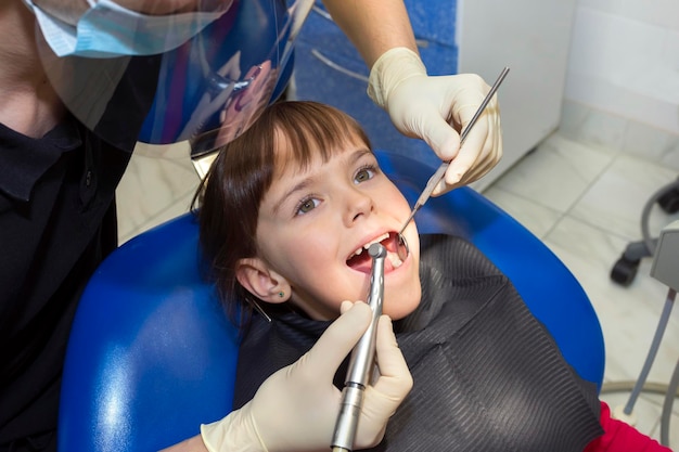 Ein Zahnarzt, der die Zähne eines kleinen Mädchens in einer Klinik untersucht Medizin, Zahnheilkunde und Gesundheitswesen