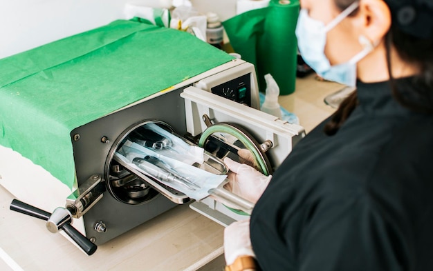 Ein Zahnarzt, der seine Werkzeuge sterilisiert Zahnarzt mit einem zahnärztlichen Sterilisator Ein Zahnarzt mit einem zahnärztlichen Autoklaven Nahaufnahme eines Zahnarztes mit einem Dampfsterilisator