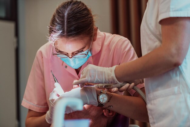 Ein Zahnarzt führt mit Hilfe eines Kollegen eine Operation am Kiefer eines älteren Patienten in einer modernen Zahnklinik durch. Foto in hoher Qualität