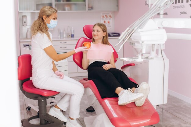 Ein Zahnarzt gibt einem Teenager in einer Zahnklinik einen Apfel