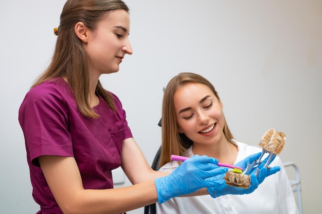 Ein Zahnhygienist zeigt einer jungen Frau die richtige Technik für