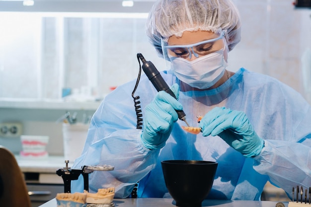 Ein Zahntechniker in Schutzkleidung arbeitet in seinem Labor an einem Prothesenzahn