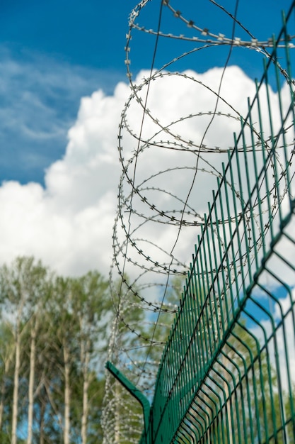 Ein Zaun mit Stacheldraht auf blauem Himmelshintergrund Eingeschränkter Durchgangsbereich