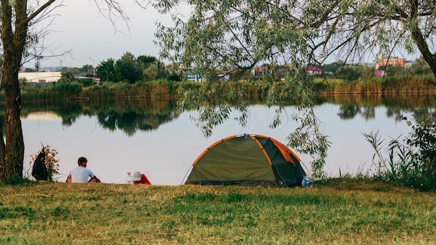 Ein Zelt am See an einem Sommerabend und zwei Männer werden fischen