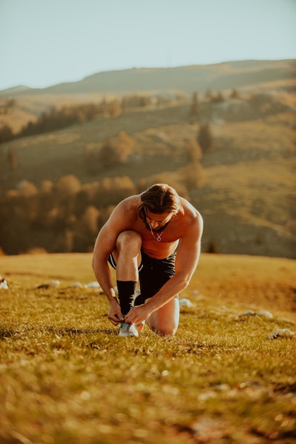 Ein zielstrebiger Athlet bereitet sich bei Sonnenaufgang auf dem Gipfel des Berges auf den Trainingsstart vor