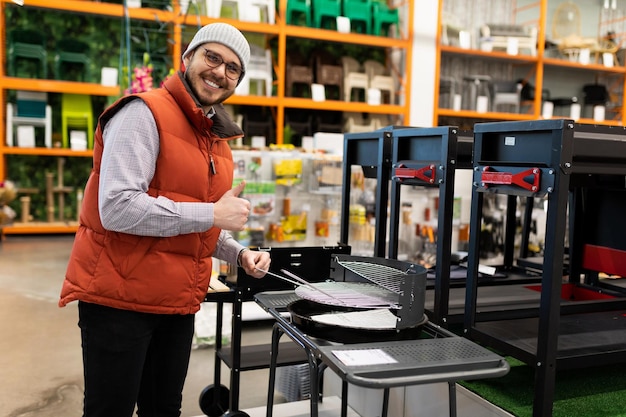 Ein zufriedener Kunde in einem Verbrauchermarkt wählt einen Grill für seinen Garten