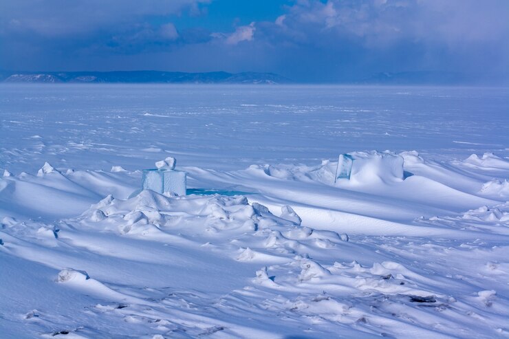 Ein zugefrorener See mit Schneeverwehungen und geschnitzten Eisstücken im Schnee