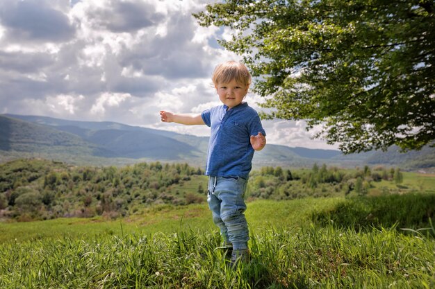 Foto ein zweijähriger junge in einem blauen t-shirt und jeans steht auf einem berg in den ukrainischen karpaten l