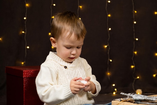 Ein zweijähriger Junge öffnet zu Hause Weihnachtsgeschenke