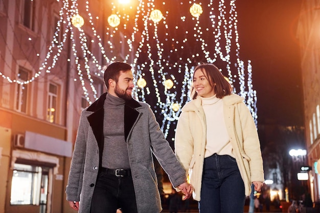 Einander an den Händen halten Glückliches junges Paar, das das neue Jahr im Freien auf der Straße feiert