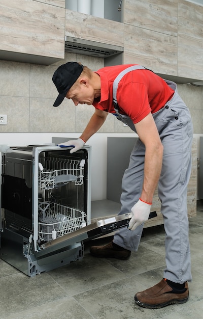 Einbau der Küche. Handwerker stellt die Spülmaschine ein.