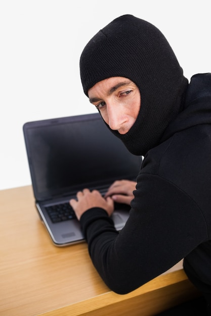 Einbrecher, der einen Laptop hackt und hinter ihm schaut