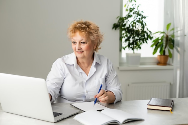 Eine ältere Frau hält einen Laptop für die Online-Kommunikation.