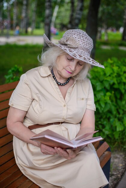 Eine ältere Frau liest ein Buch im Park