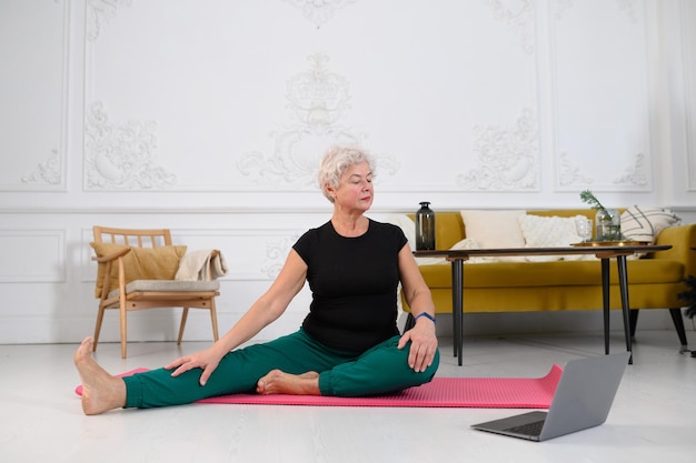 Eine ältere Frau macht Yoga zu Hause das Konzept eines gesunden Lebensstils im Alter