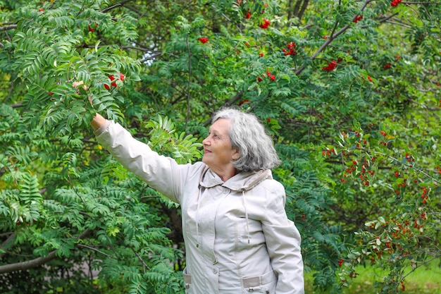 Eine ältere Frau mit grauem Haar ist bei kühlem Wetter warm gekleidet