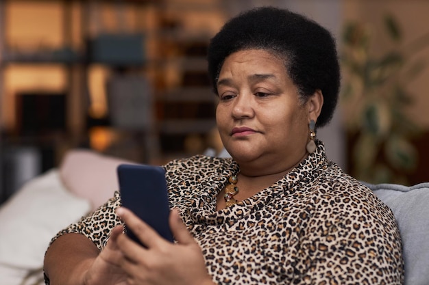Eine ältere schwarze Frau schaut zu Hause auf den Telefonbildschirm
